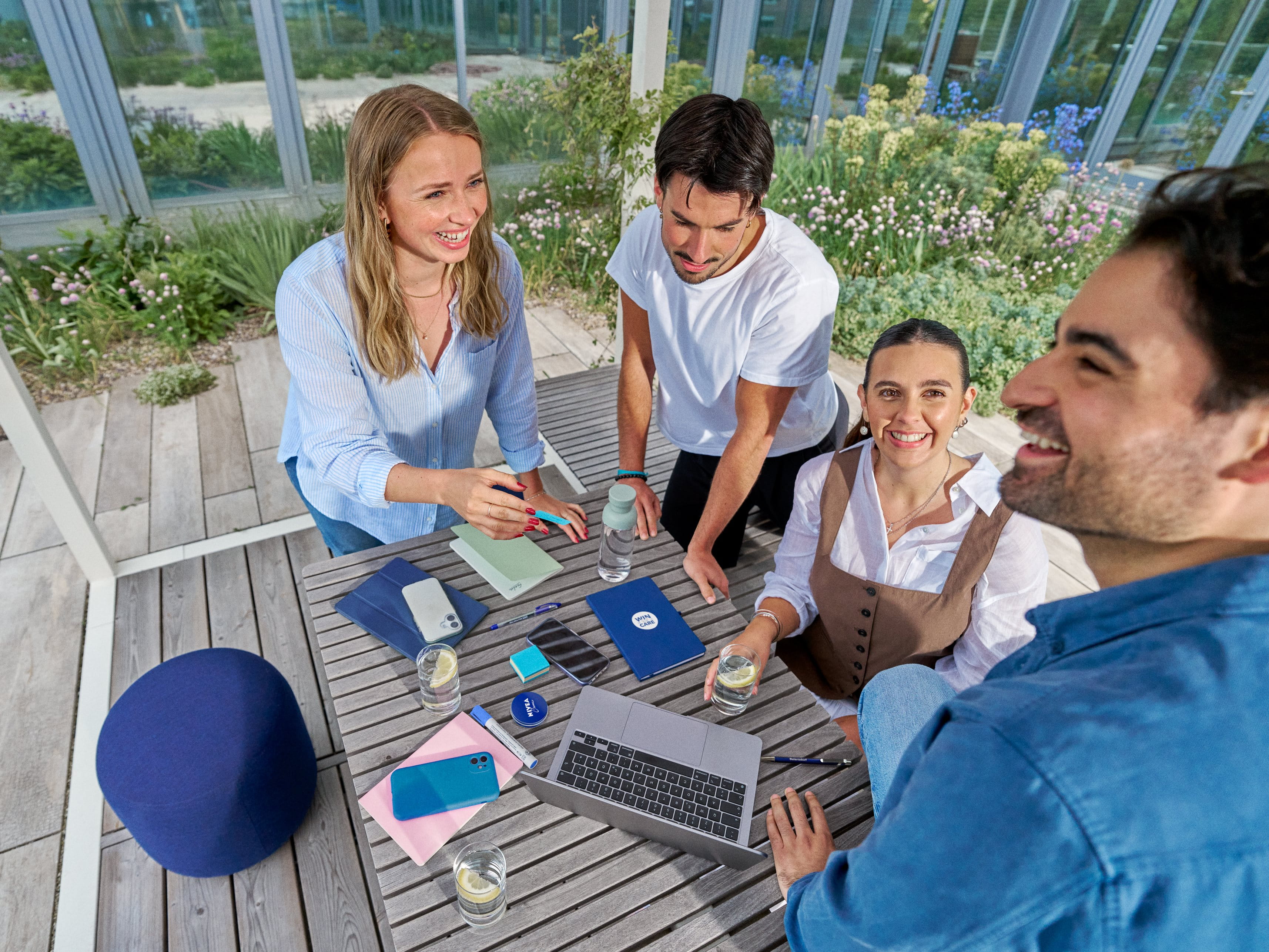 Four colleagues collaborating and smiling together at an outdoor table.