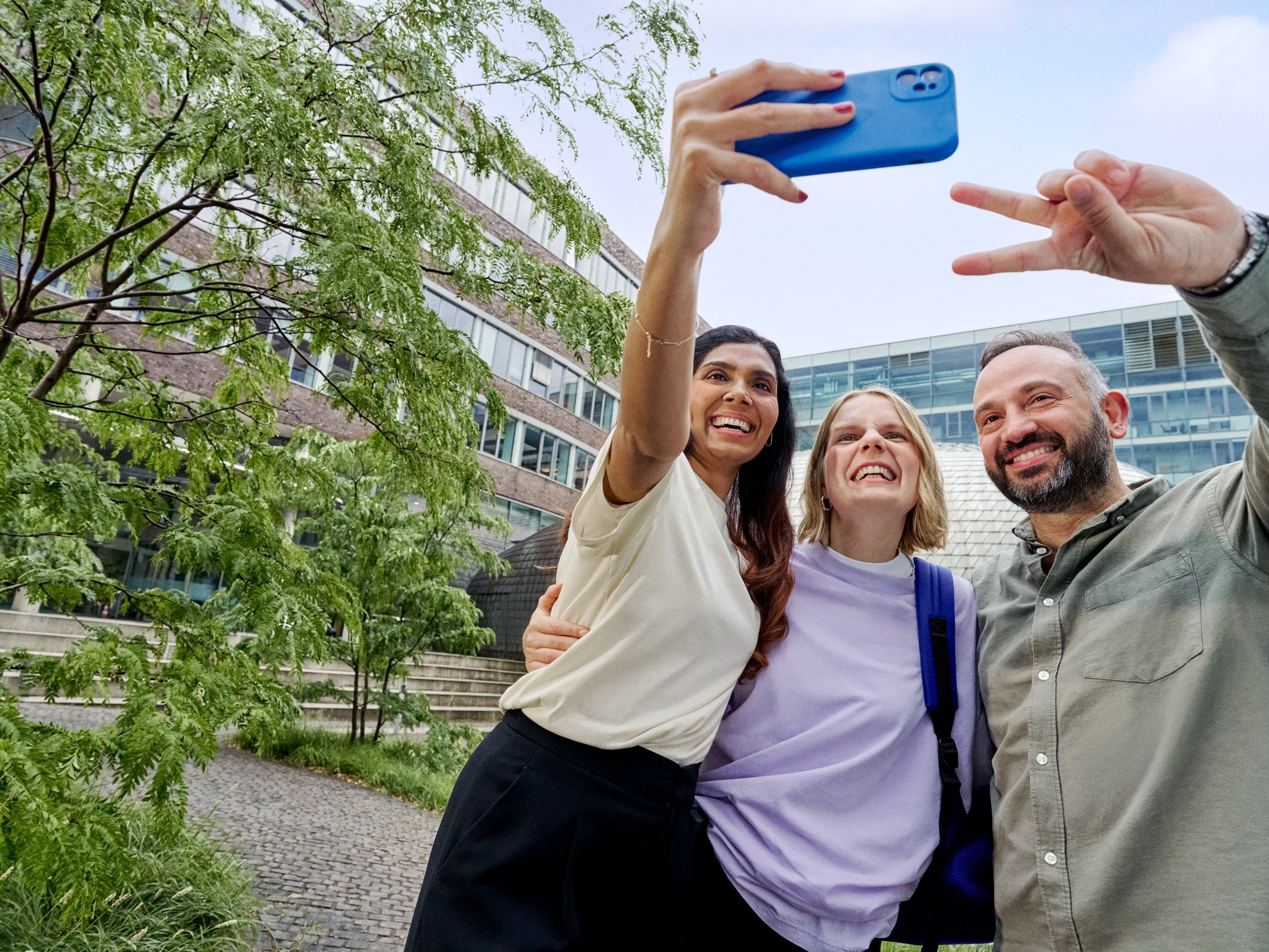 Three smiling colleagues taking a selfie.