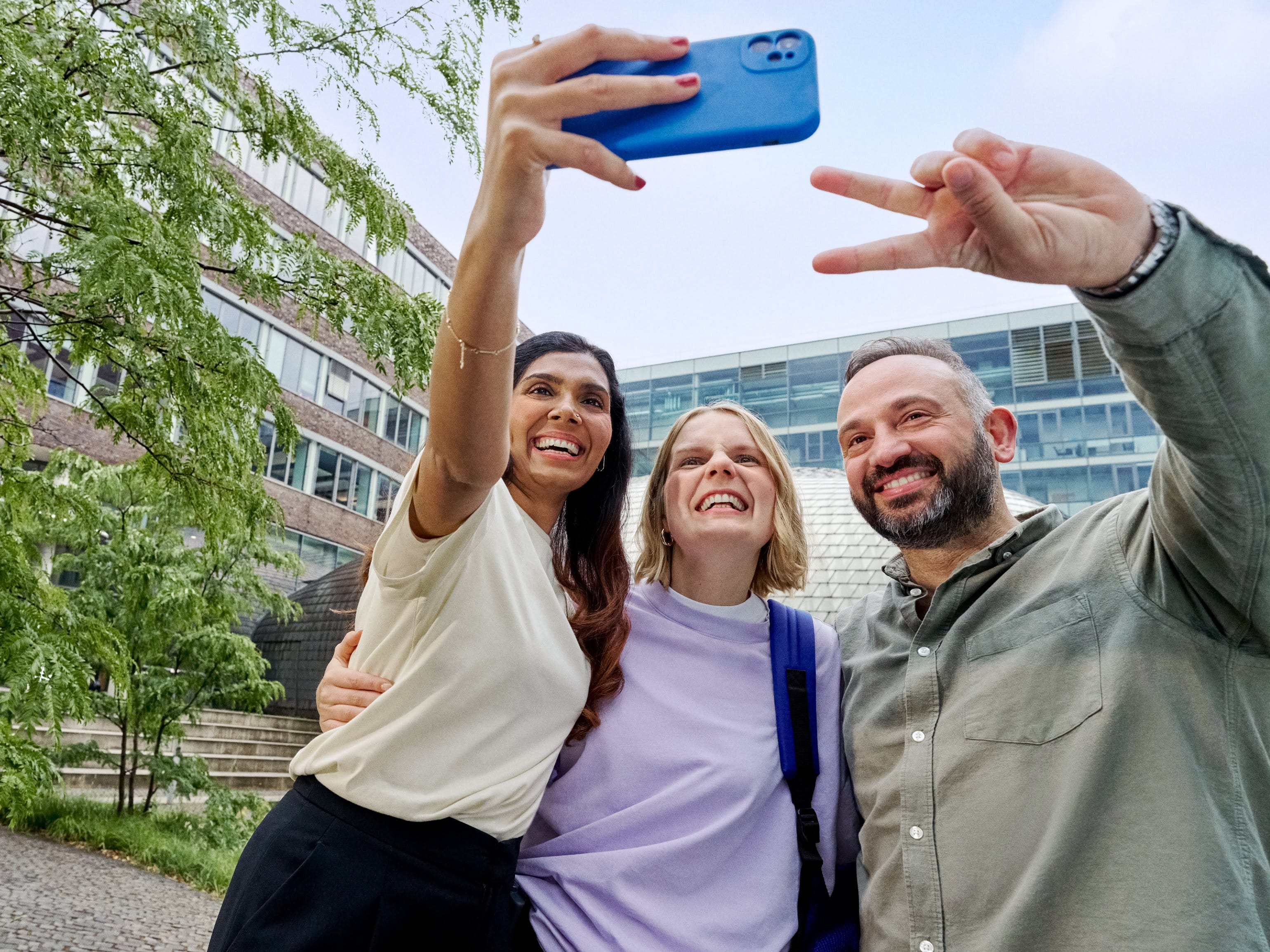 Three smiling colleagues taking a selfie.
