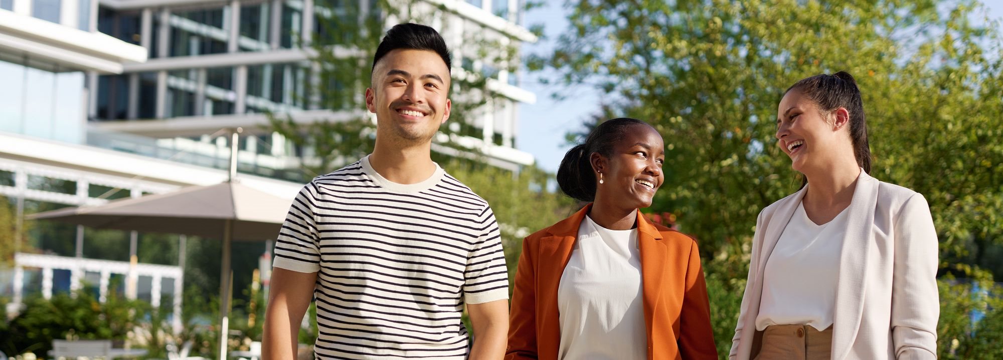 Drei junge Leute schauen sich an und lächeln