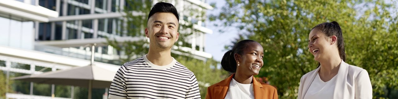 Drei junge Leute schauen sich an und lächeln