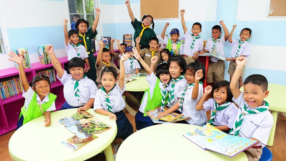Thailändische Kinder mit Büchern an Tischen
