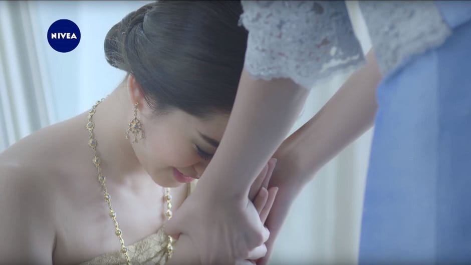 Tochter kniet in Hochzeitskleid vor Mutter