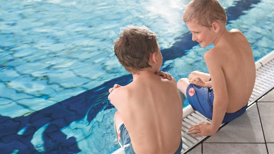Zwei Jungen am Beckenrand im Schwimmbad