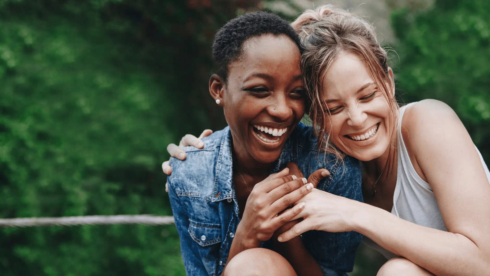 Diverse group of people holding hands in a circle outdoors, representing inclusion and togetherness.