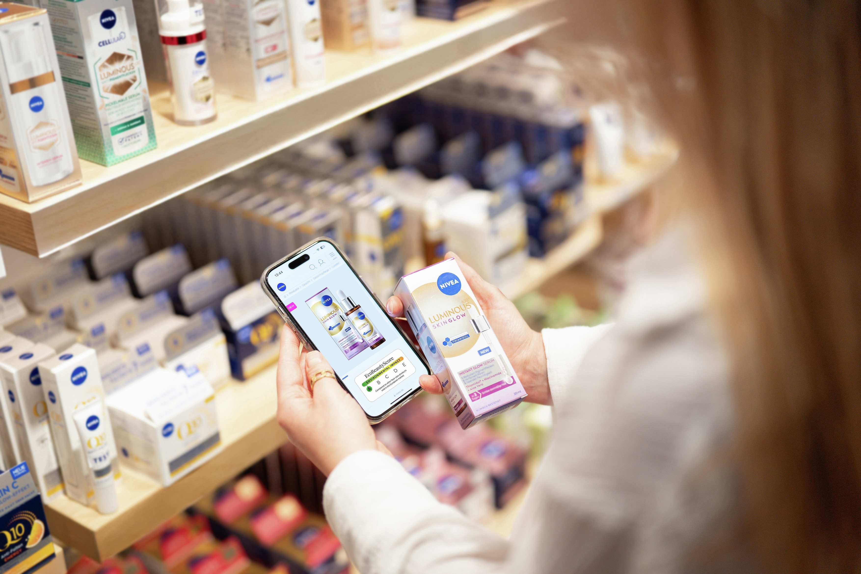 Frau mit langen Haaren hält ein Smartphone, das den EcoBeautyScore eines NIVEA-Produkts zeigt.