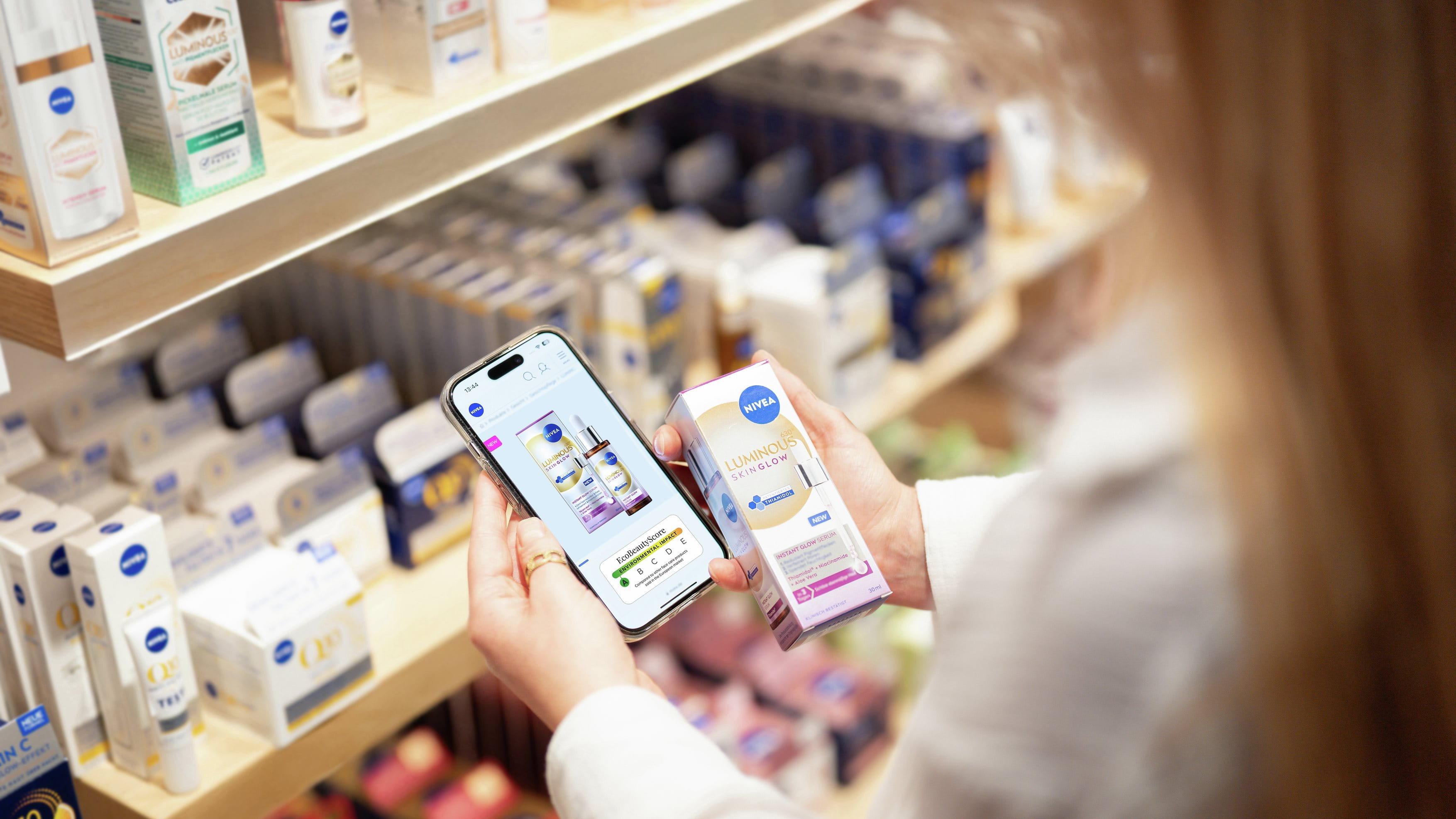 Frau mit langen Haaren hält ein Smartphone, das den EcoBeautyScore eines NIVEA-Produkts zeigt.