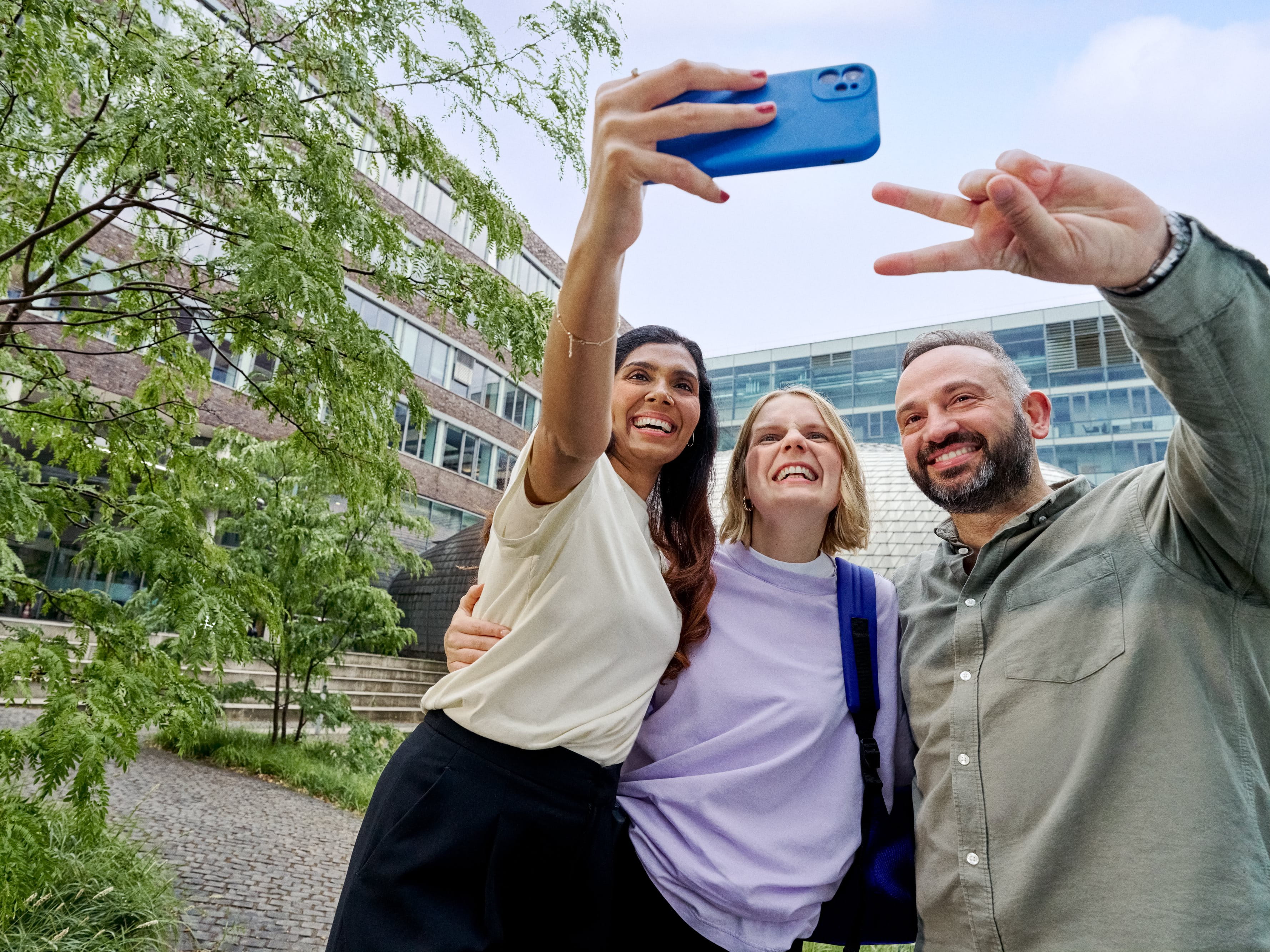 Beiersdorf Kolleginnen und Kollegen machen gemeinsam ein Selfie auf dem Campus und zeigen Teamgeist, Zusammenarbeit und eine inklusive Unternehmenskultur.