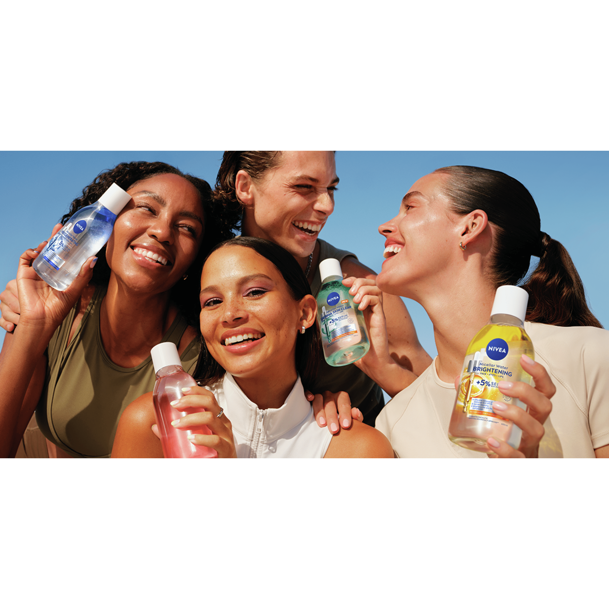Group of friends smiling closely together outdoors, with one person holding up a NIVEA skincare product bottle, conveying joy, confidence, and shared moments.