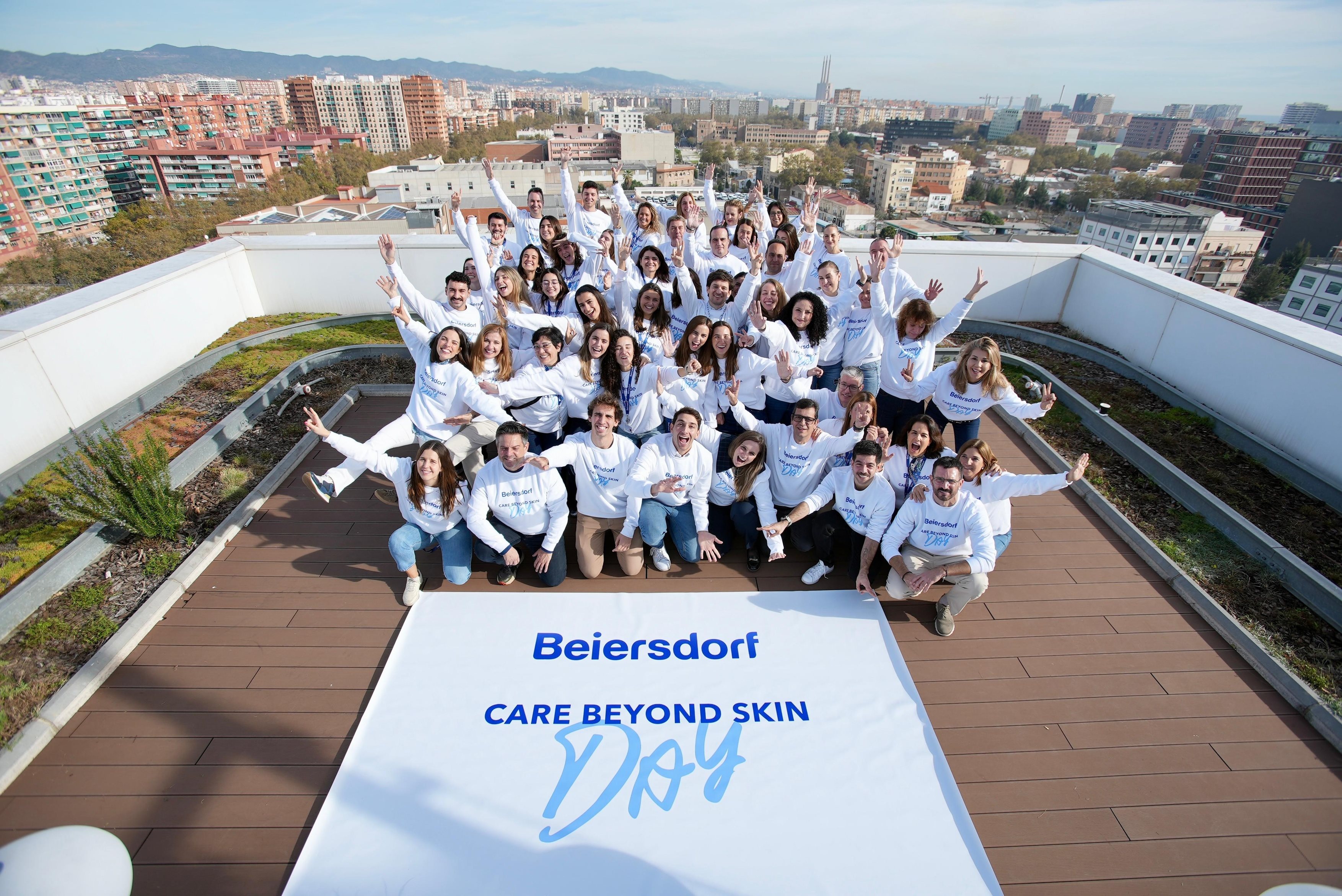 Kolleg*innen auf einer Dachterrasse mit einem CARE BEYOND SKIN Day Banner.