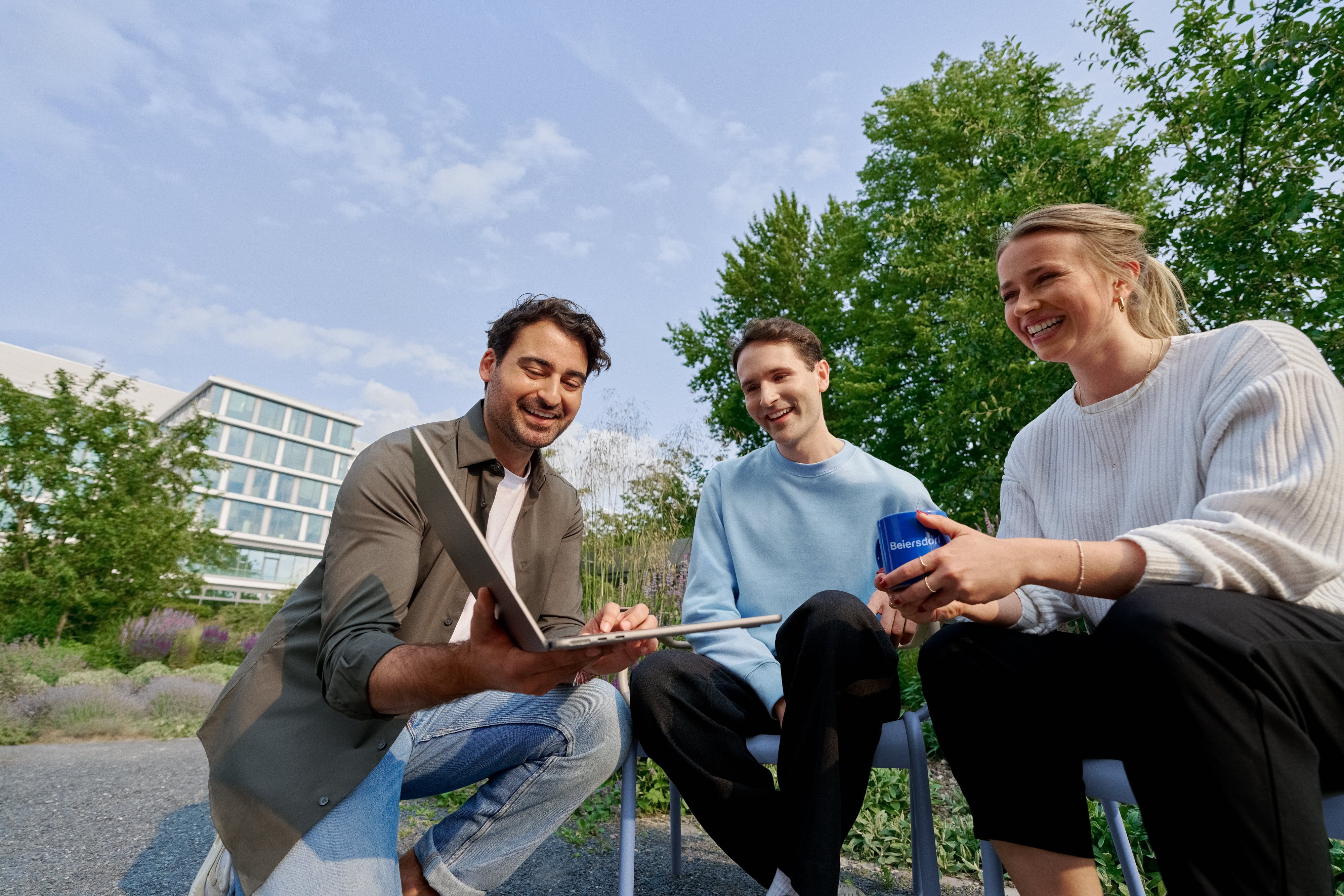 Beiersdorf Mitarbeitende arbeiten im Außenbereich gemeinsam an einem Projekt und stehen für Teamarbeit, Flexibilität und ein modernes Arbeitsumfeld.