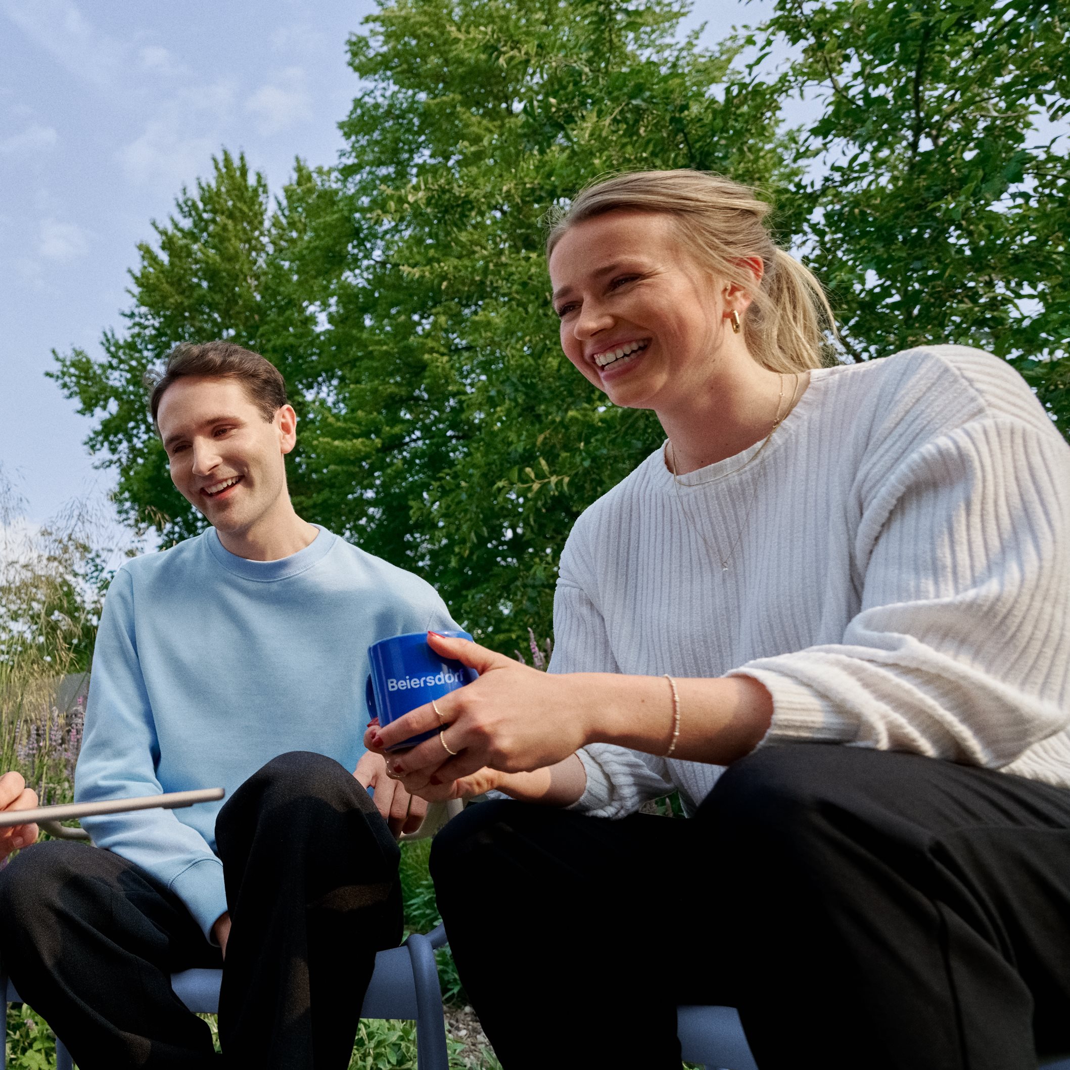 Beiersdorf Mitarbeitende arbeiten im Außenbereich gemeinsam an einem Projekt und stehen für Teamarbeit, Flexibilität und ein modernes Arbeitsumfeld.