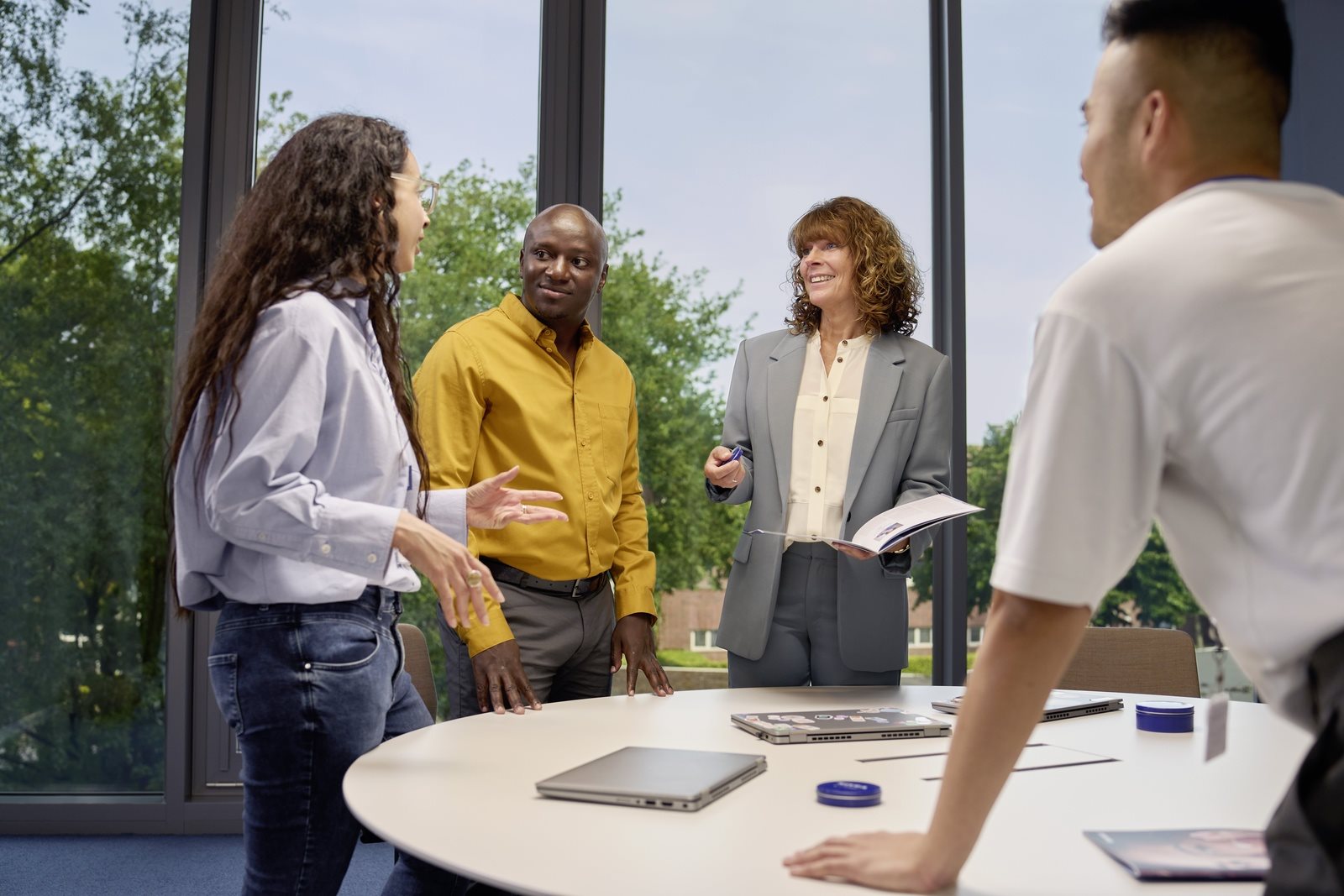 A group of people standing, smiling and discussing