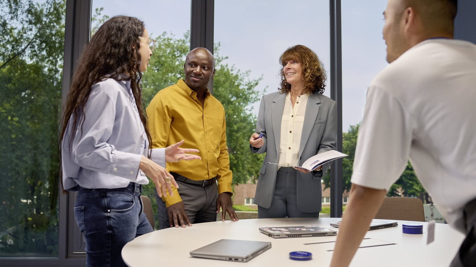 A group of people standing, smiling and discussing