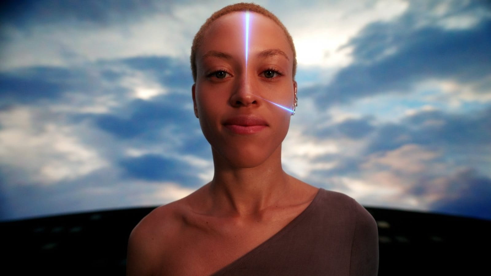 Person with glowing blue lines on their face against a cloudy sky.