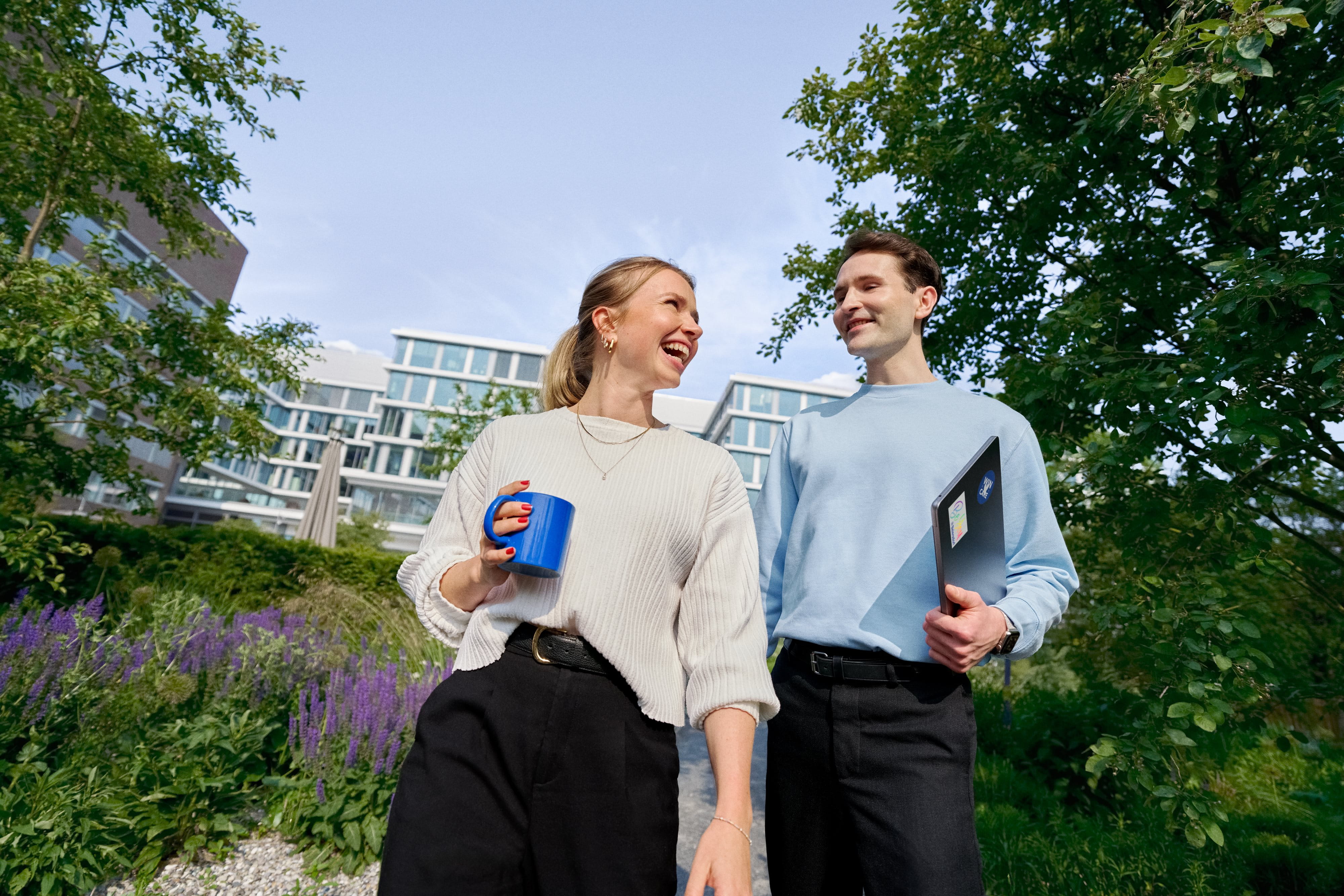 Beiersdorf Mitarbeitende tauschen sich bei einem Spaziergang auf dem Unternehmenscampus aus und stehen für Zusammenarbeit, Unternehmenskultur und flexible Arbeitsweisen