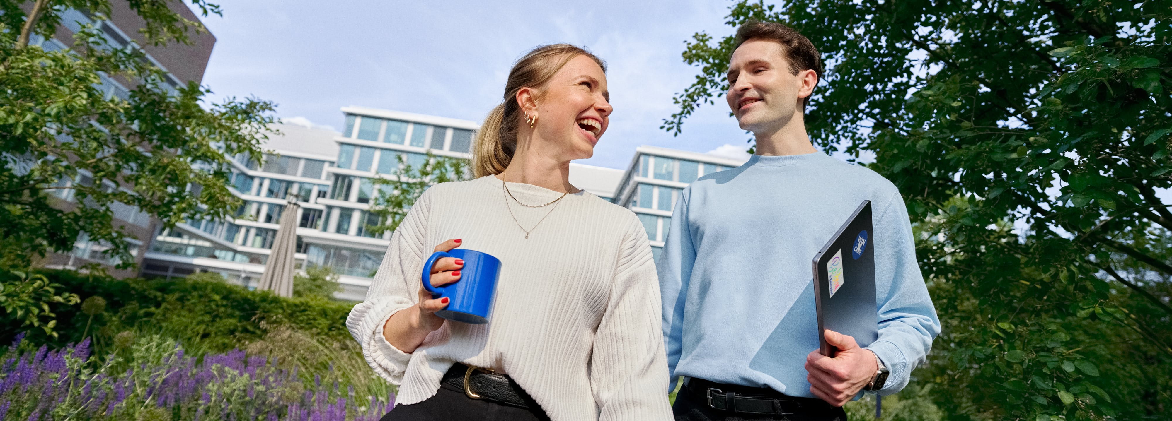 Beiersdorf Mitarbeitende tauschen sich bei einem Spaziergang auf dem Unternehmenscampus aus und stehen für Zusammenarbeit, Unternehmenskultur und flexible Arbeitsweisen