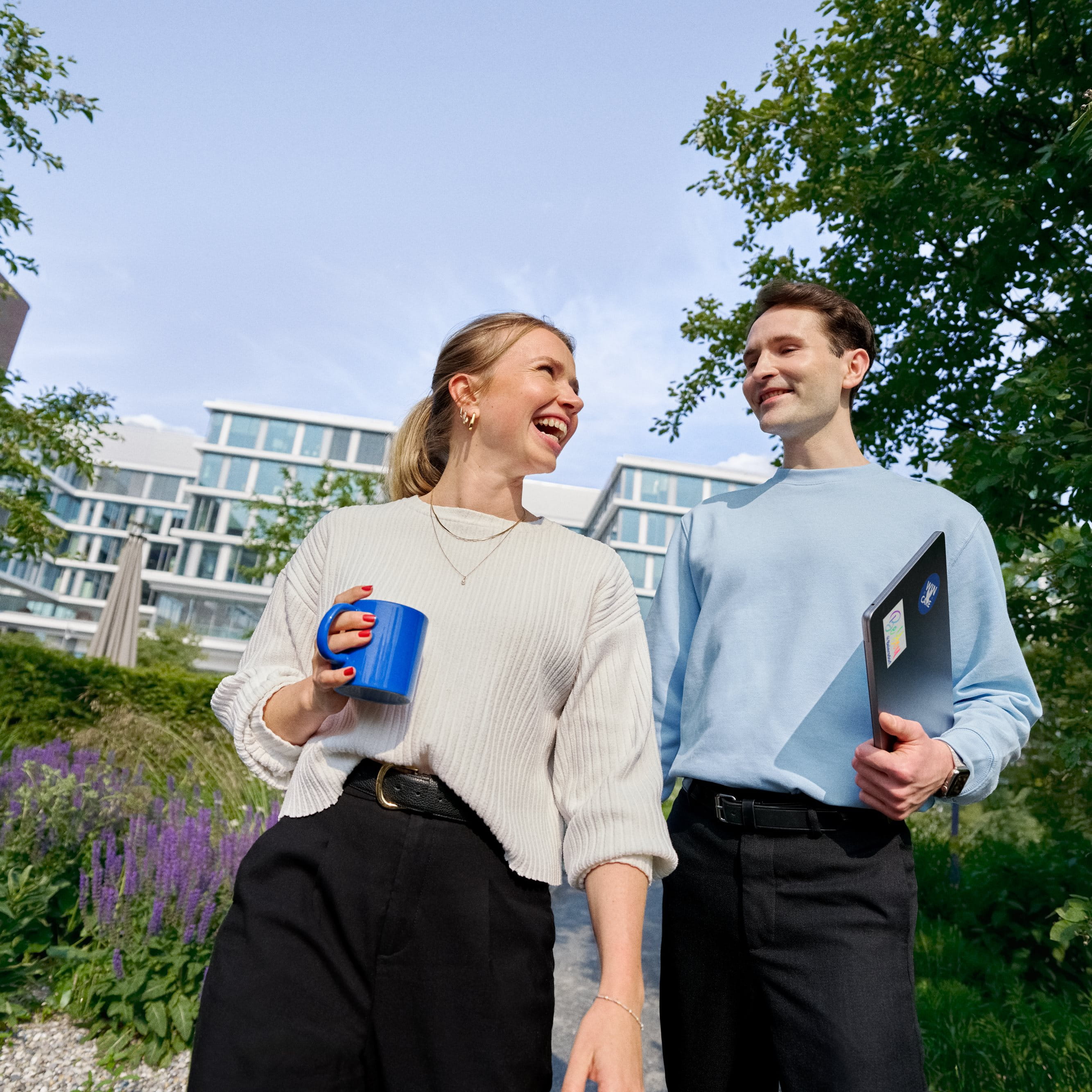 Beiersdorf Mitarbeitende tauschen sich bei einem Spaziergang auf dem Unternehmenscampus aus und stehen für Zusammenarbeit, Unternehmenskultur und flexible Arbeitsweisen