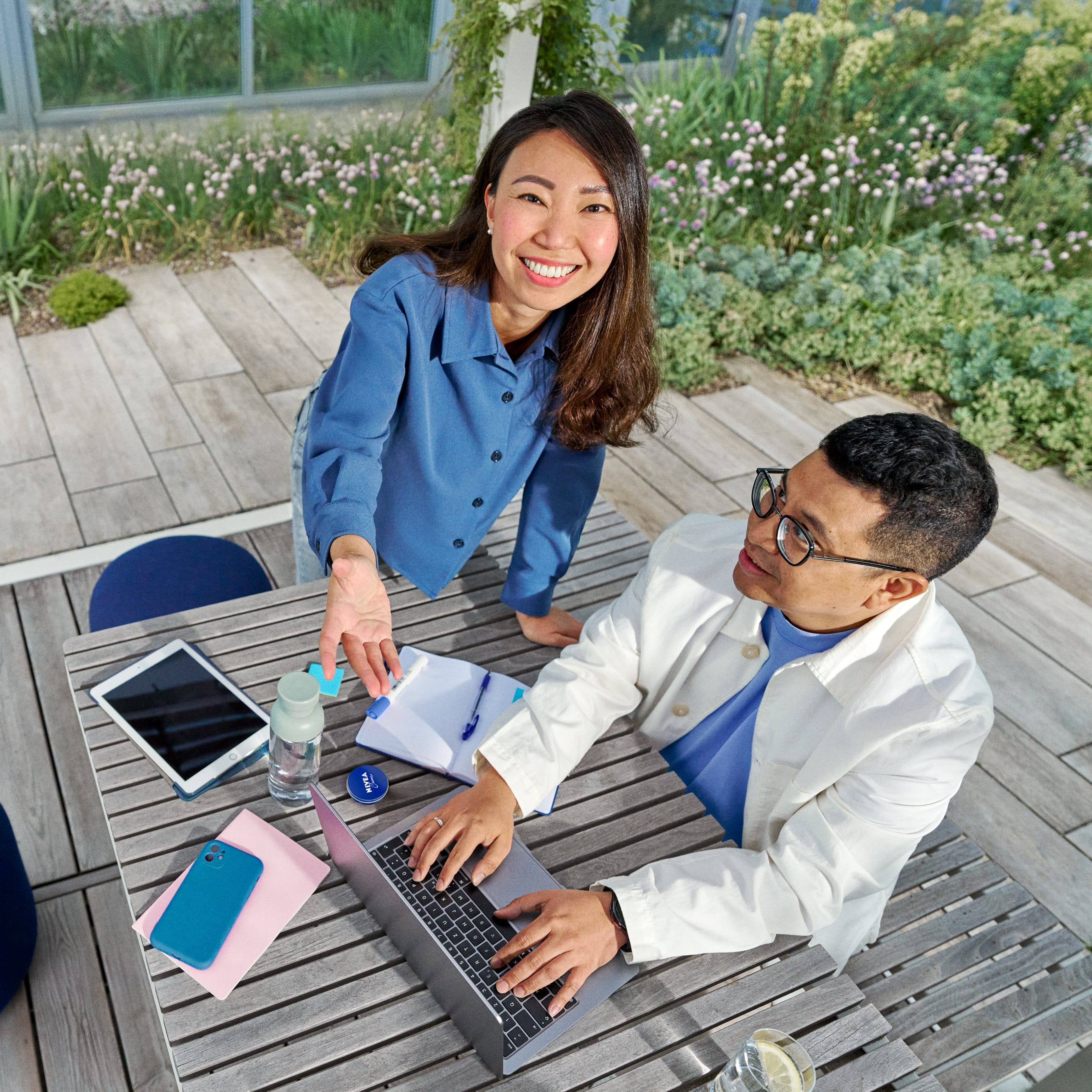 Beiersdorf Mitarbeitende arbeiten in einem Außenbereich gemeinsam an Projekten und verbinden Teamarbeit, Innovation und flexibles Arbeiten in einem modernen Arbeitsumfeld.