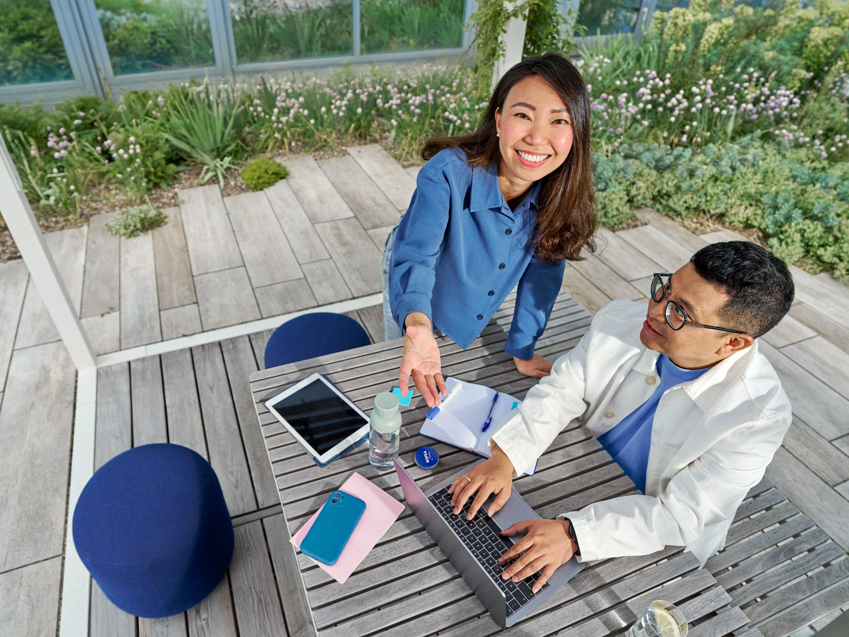 Beiersdorf Mitarbeitende arbeiten in einem Außenbereich gemeinsam an Projekten und verbinden Teamarbeit, Innovation und flexibles Arbeiten in einem modernen Arbeitsumfeld.