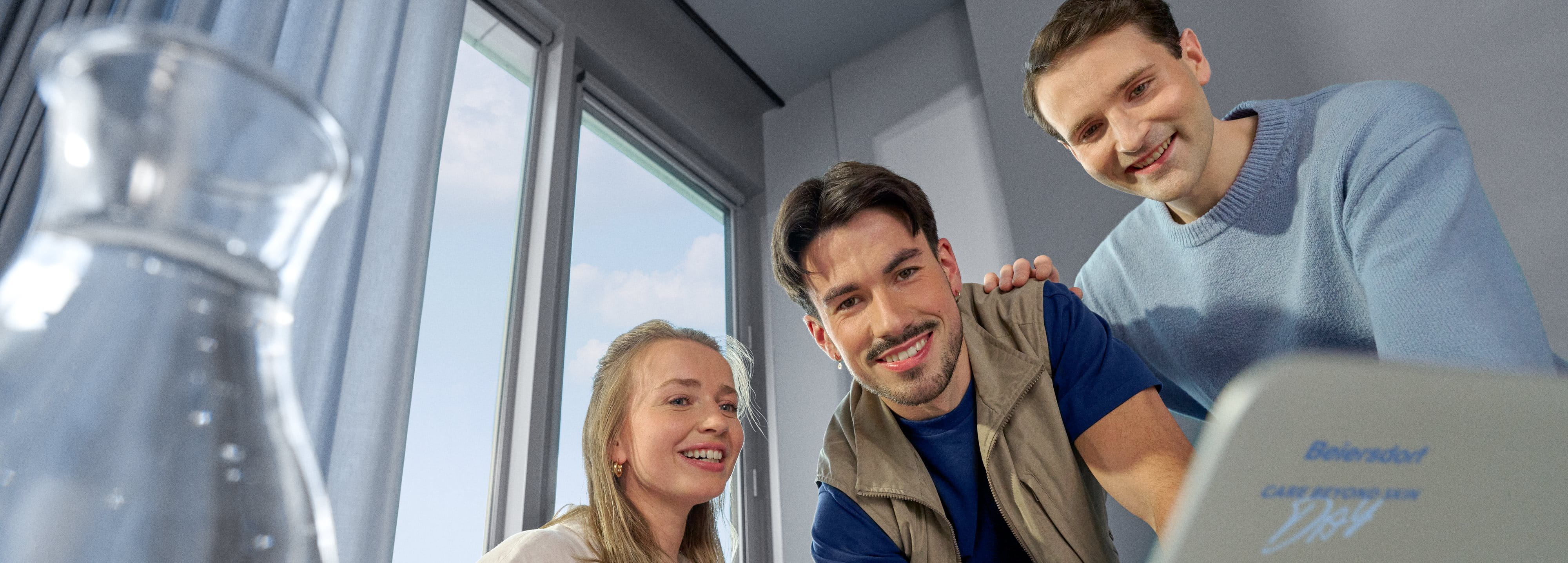 Beiersdorf Mitarbeitende besprechen Projektinhalte an einem Laptop und stehen für Zusammenarbeit, Innovation und Karrieremöglichkeiten in einem globalen Team.